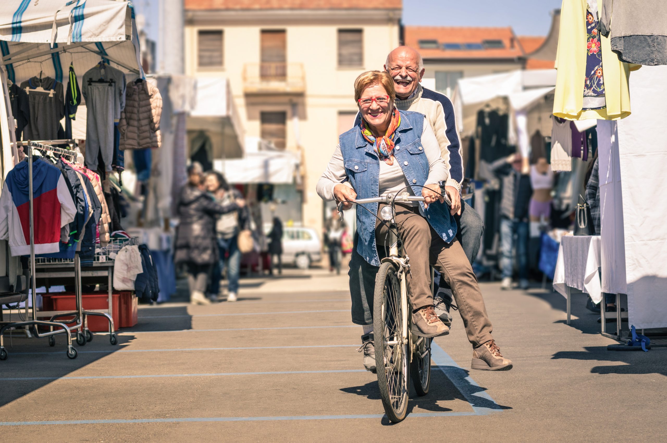 Happy senior couple having fun with bicycle at city flea market