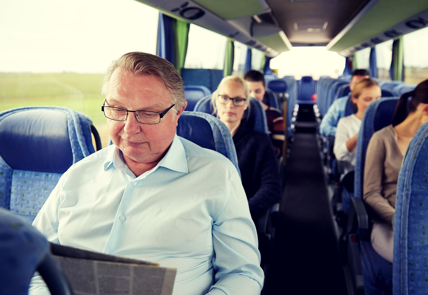 happy senior man reading newspaper in travel bus