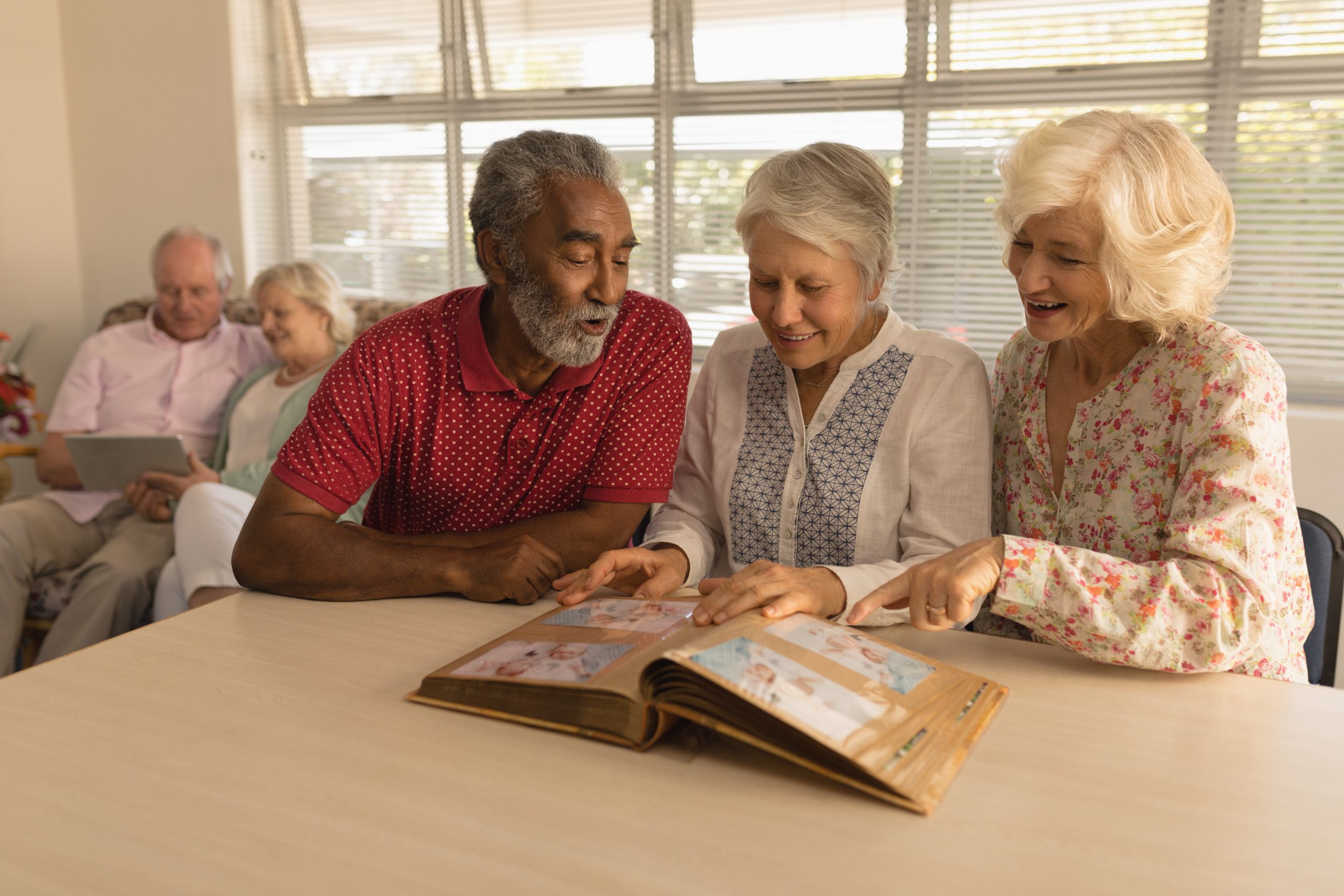 Group of senior people looking at photo album at nursing home
